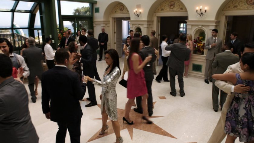 Attendees in Miami mansion dance in large room.