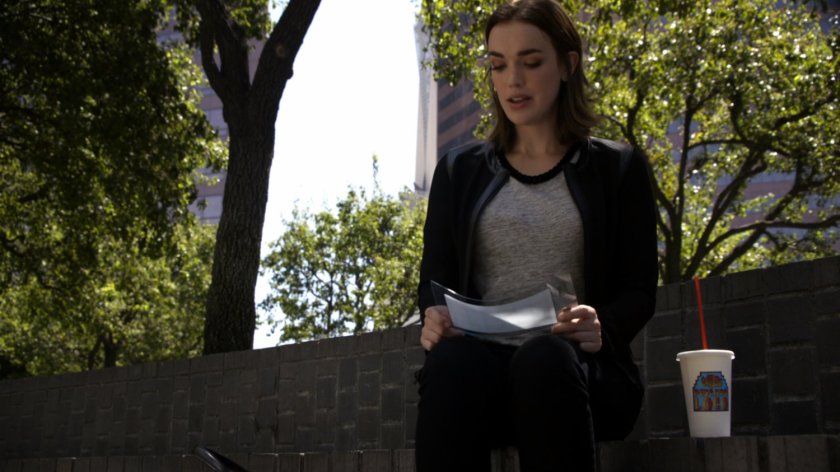 Simmons reading a secret message in a park, with a Pescado Loco cup.