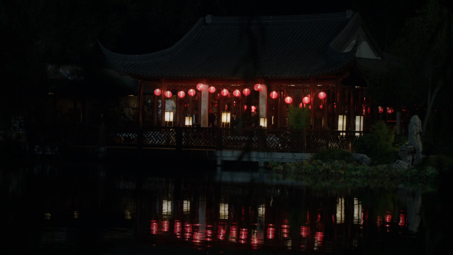 Japanese pagoda at night reflected in water.