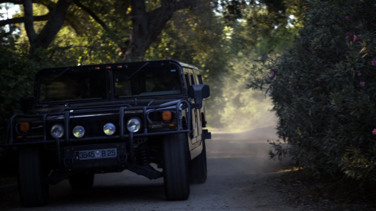 HumVee driving through wooded trail.