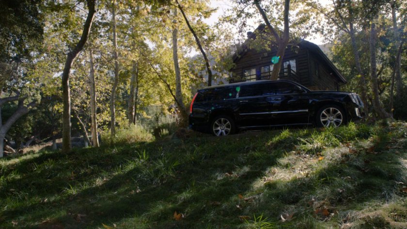 A black SUV outside a cabin in the Massachusetts woods.