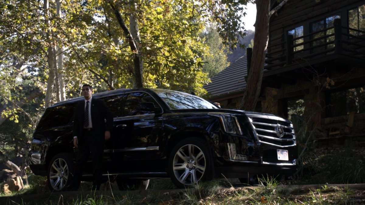 A black SUV outside a cabin in the Massachusetts woods.