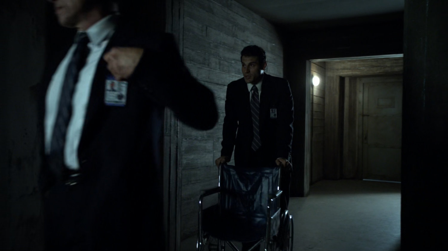 A SHIELD agent pushing a wheelchair through the hallway of "The Rat."