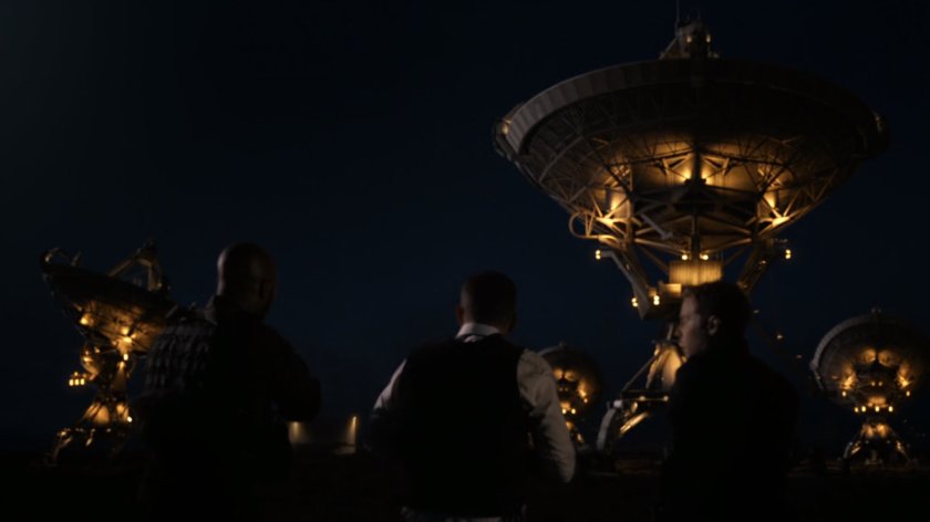 SHIELD agents silhouetted by lit-up deep space antenna.