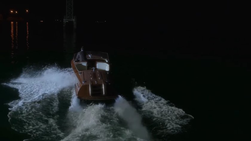 Behind the scenes: Stark drives boat away from Wharf 17 towards city at night.