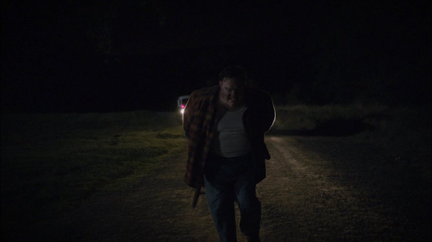 Sheldon McFee running on dirt road with chair strapped to back.