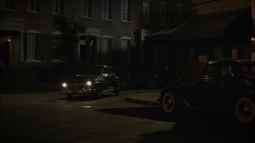 Car takes corner on dark New York city street.