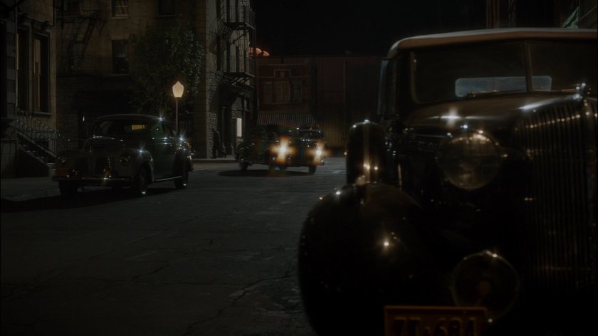 Car turns corner on dark New York city street across from The Griffith Hotel.