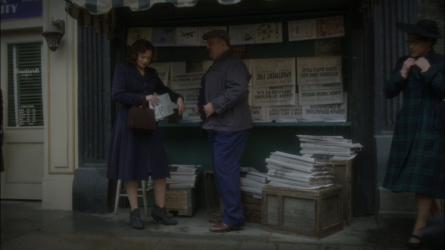 Peggy buying a paper at a newsstand on New York sidewalk.