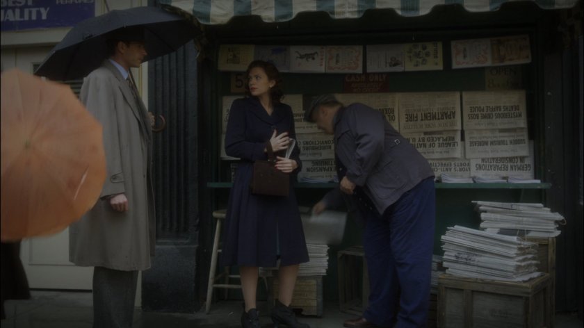 Peggy and Jarvis by a newsstand on New York sidewalk.