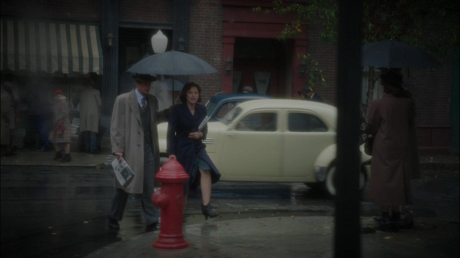Peggy and Jarvis cross a rainy street in New York.