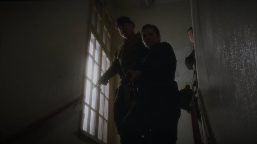 Peggy and Dum Dum Dugan descend a stairway.