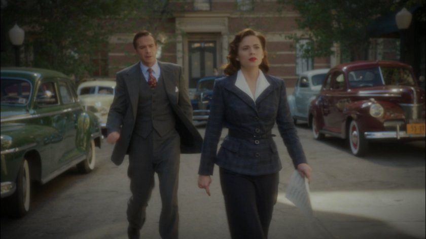 Peggy and Jarvis walk across a street.