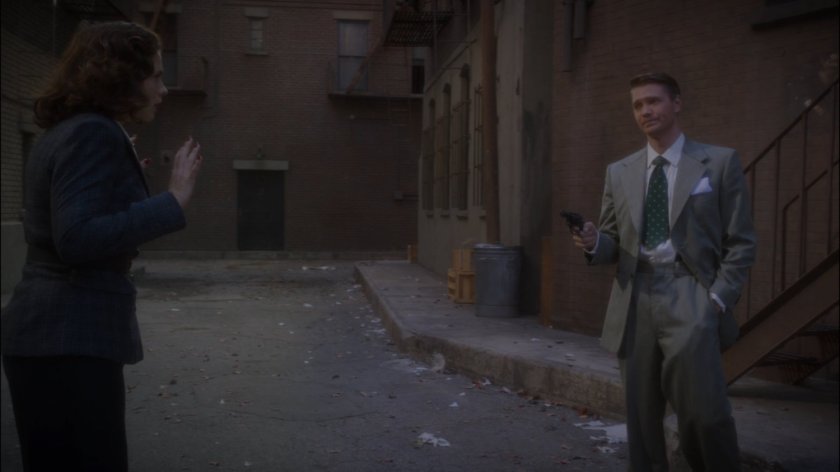 Thompson confronts Peggy in alley behind Automat.