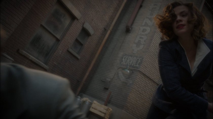 Peggy knocks out Thompson in alley behind Automat.