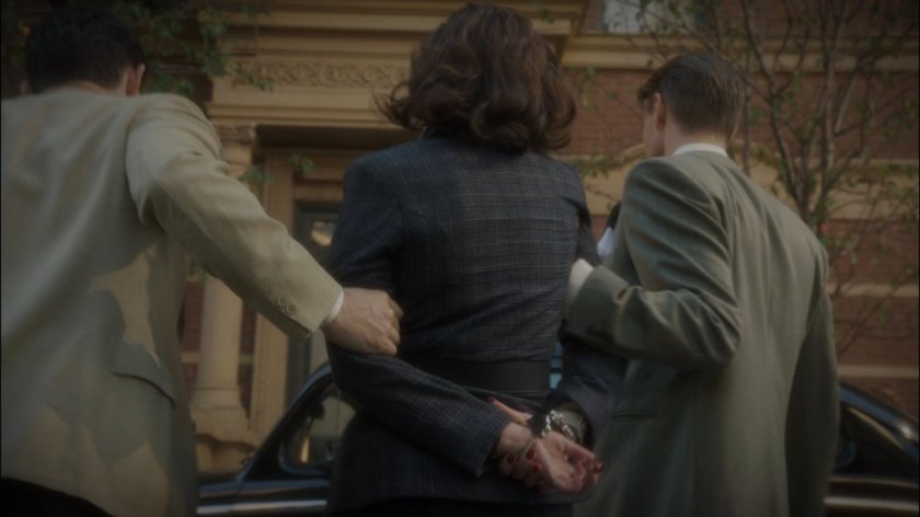 Peggy in handcuffs being led across street by Thompson and Sousa.