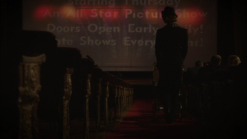 Dottie pushes baby stroller in movie theater.