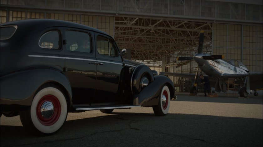Car pulls into airfield hangar.