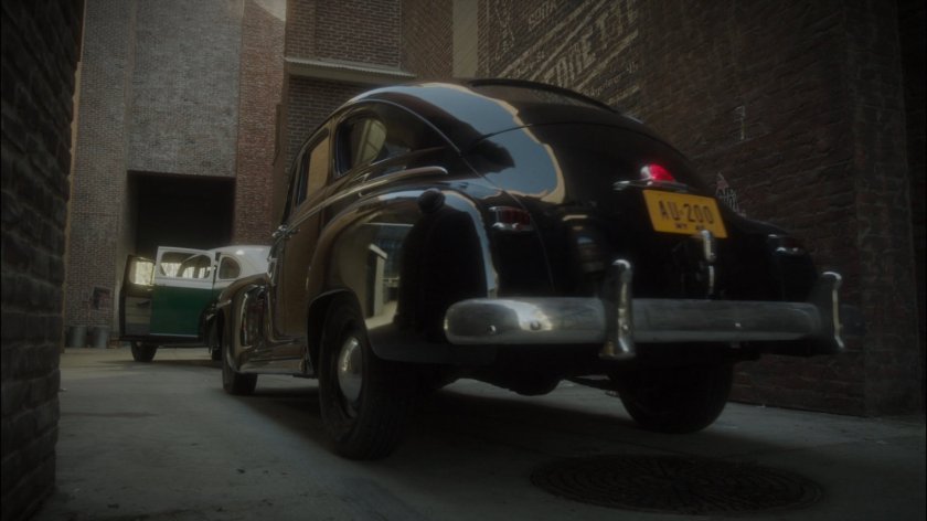 Car pulls in to New York alley behind empty police car.