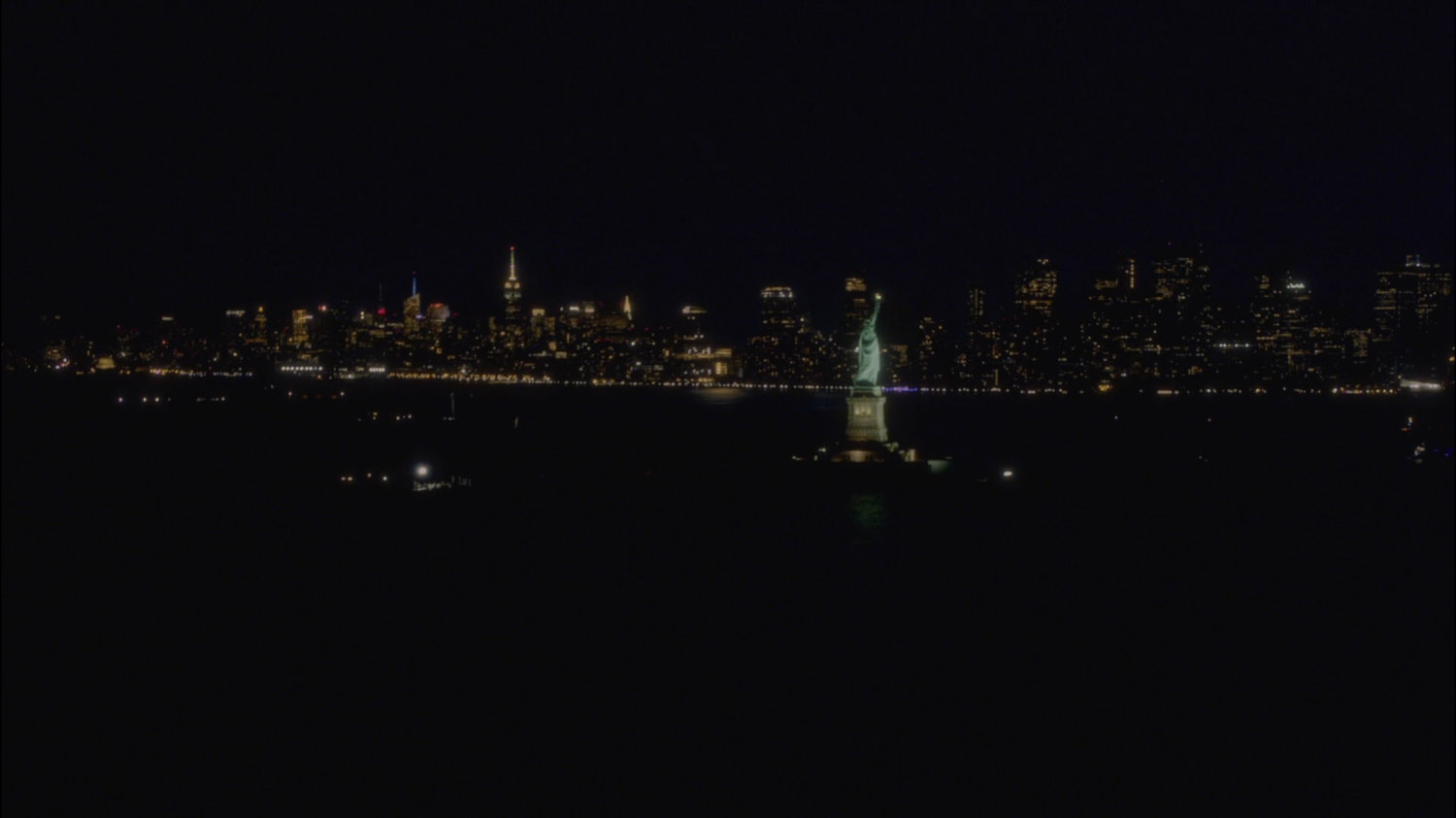 Aerial view of New York city at night, with the Statue of Liberty.
