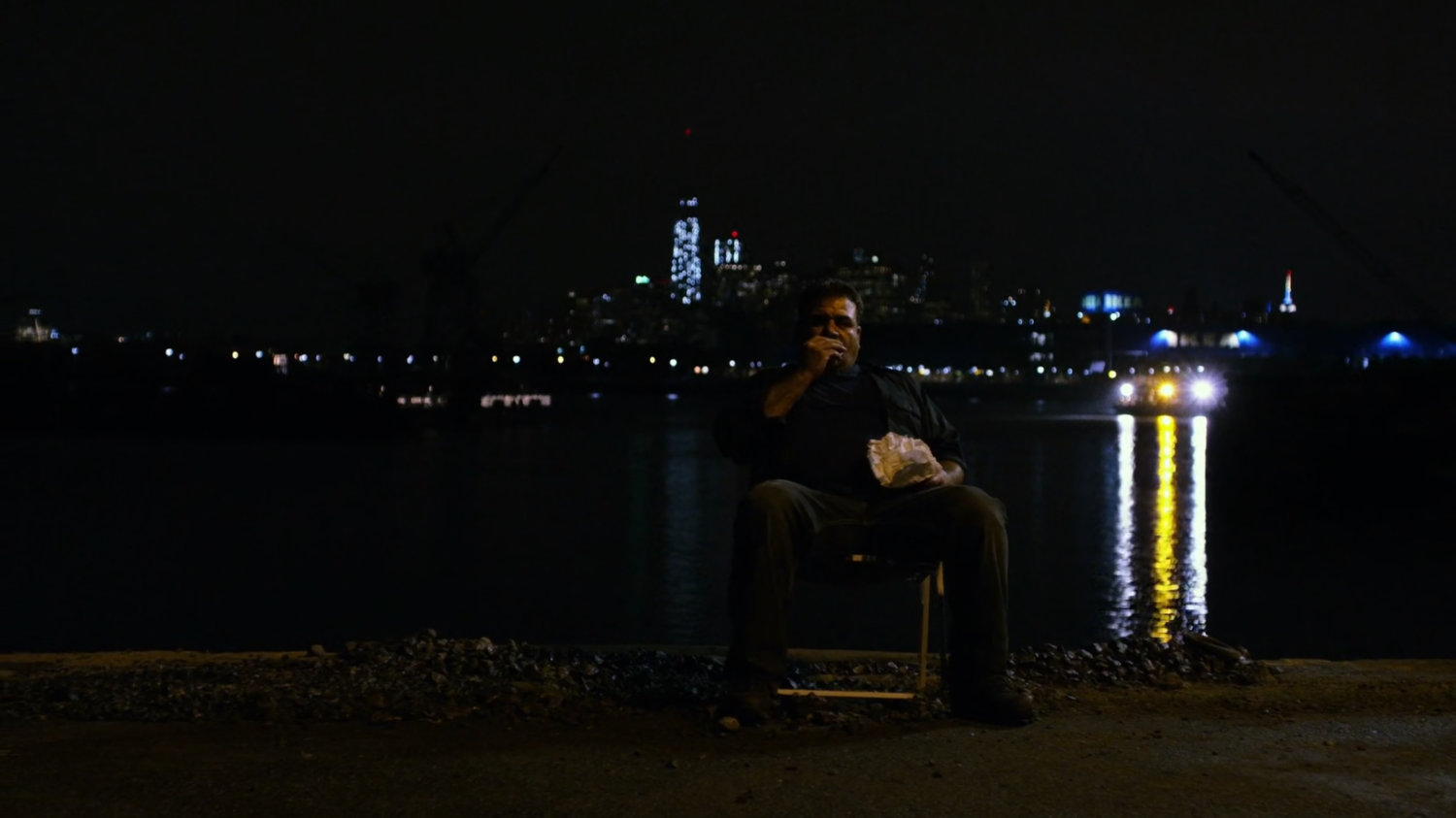 Russian slaver sitting in chair at a dark container yard in Brooklyn.