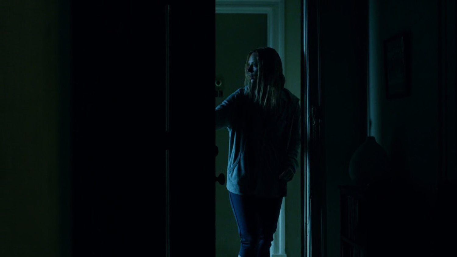 Karen entering her dark apartment.