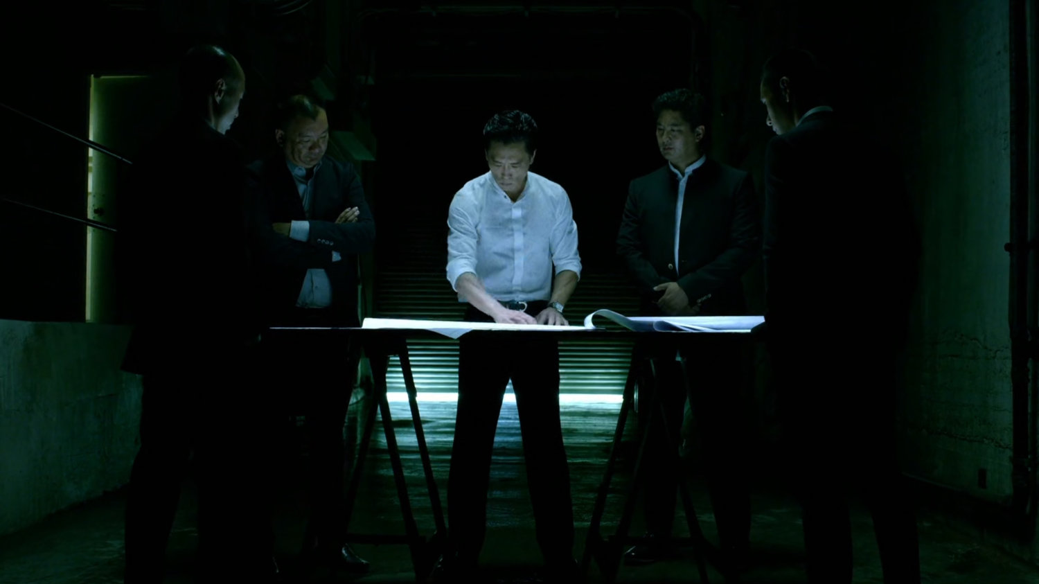 Nobu and other men look at blueprints.