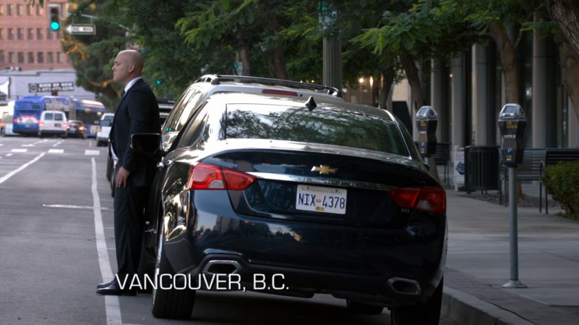 Man standing by dark car. Text: Vancouver, B.C.