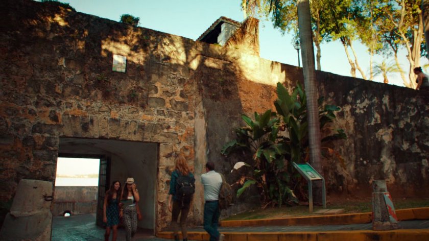 Bobbi and Coulson walk on cobblestone street outside stone wall in San Juan.