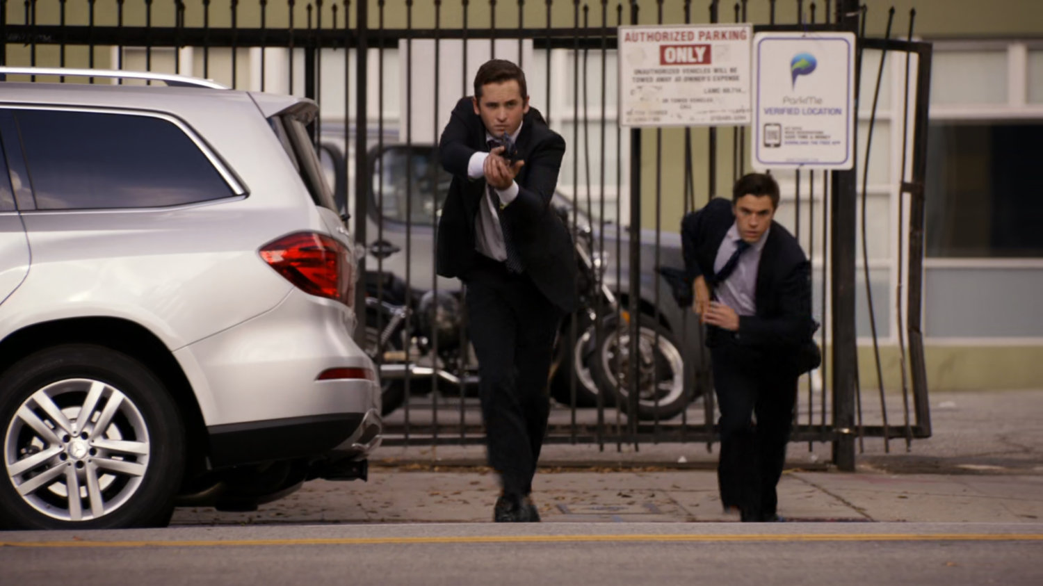 Two men in suit with guns run across Vancouver street.