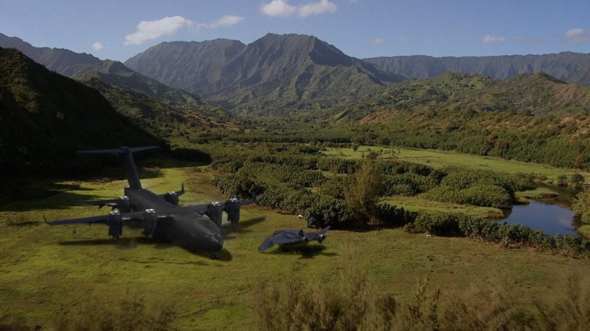 Aerial of tropical fields and mountains, with The Bus and a quinjet.