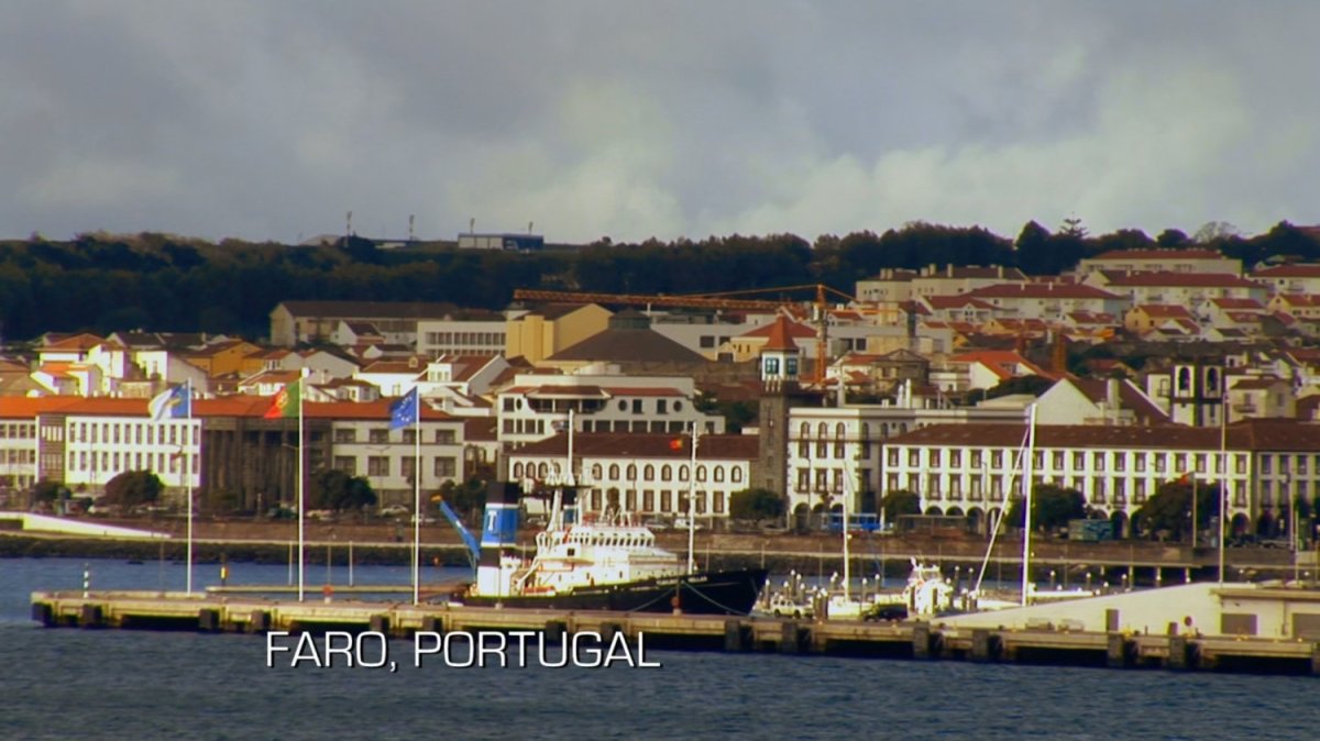 Boats docked at coastal city. Text: Faro, Portugal.