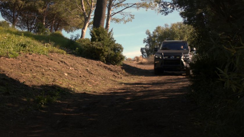 SHIELD SUV driving on dirt road in woods.