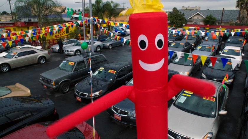 A red air dancer in front of used car dealer.