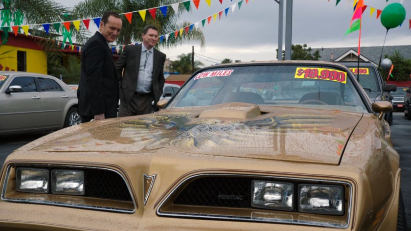 Coulson and Honest Eddie look at a golden Pontiac Firebird.