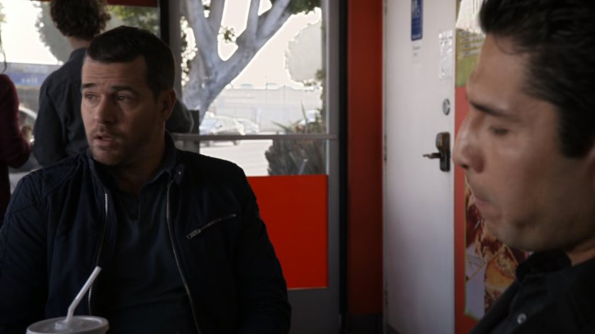 Two men sit in a restaurant booth by the bathroom.