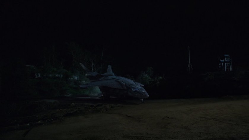 Quinjet parked next to oil field at nighttime.