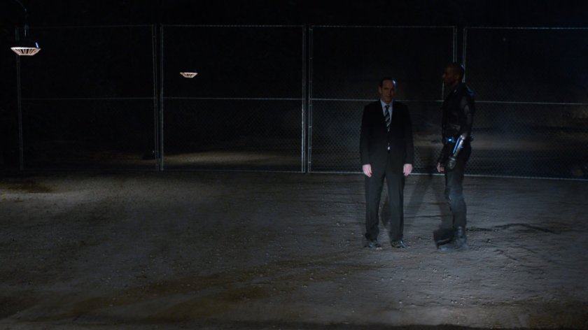 Coulson and Deathlok illuminated by car headlights at night in oil field.