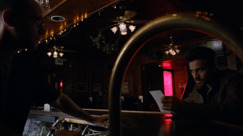 Ward at a bar looking at a photo.