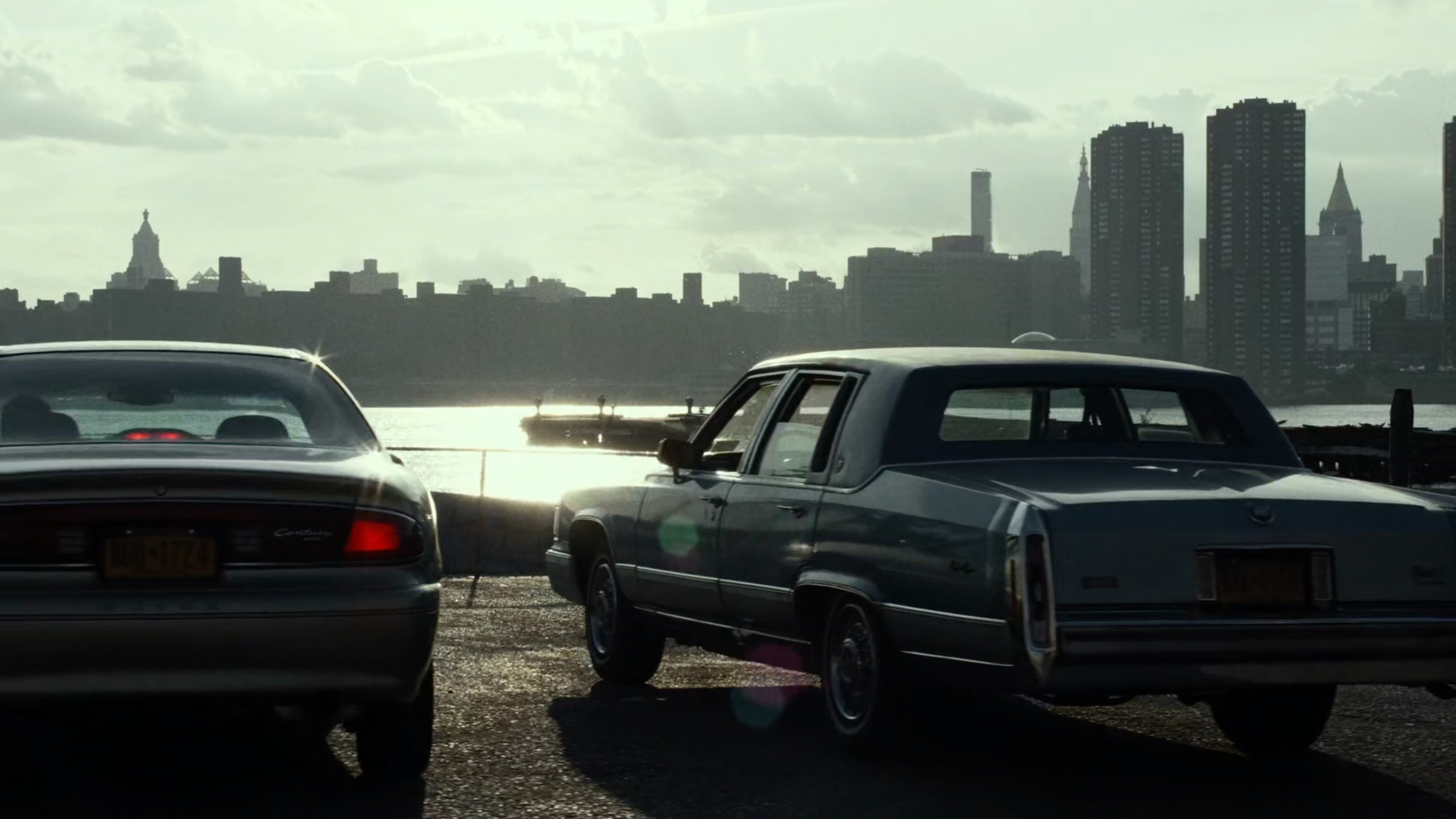 Two cars parked by the East River.