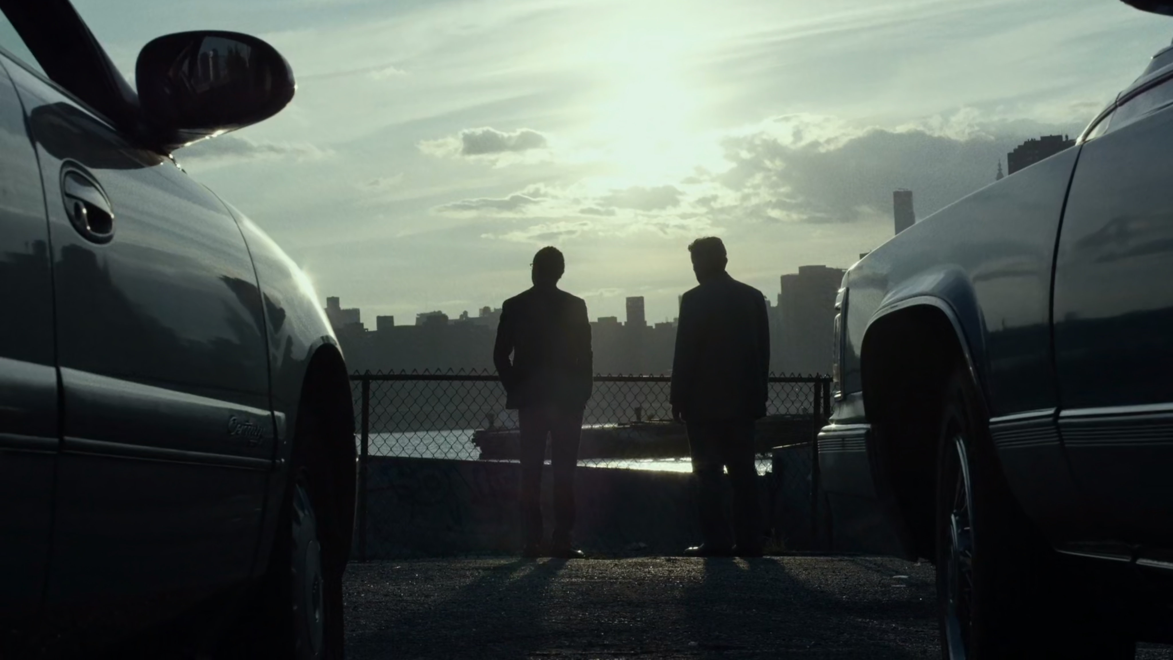 Two men by East River with New York City in background.