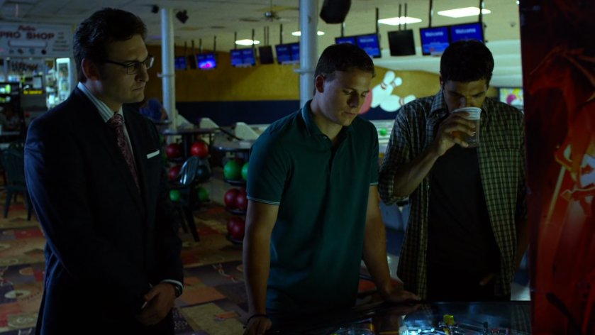 Wesley watches two men play pinball at Whitestone Lanes.
