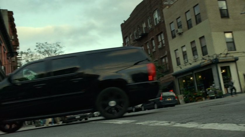 Black SUV drives through New York intersection at Grand Avenue.