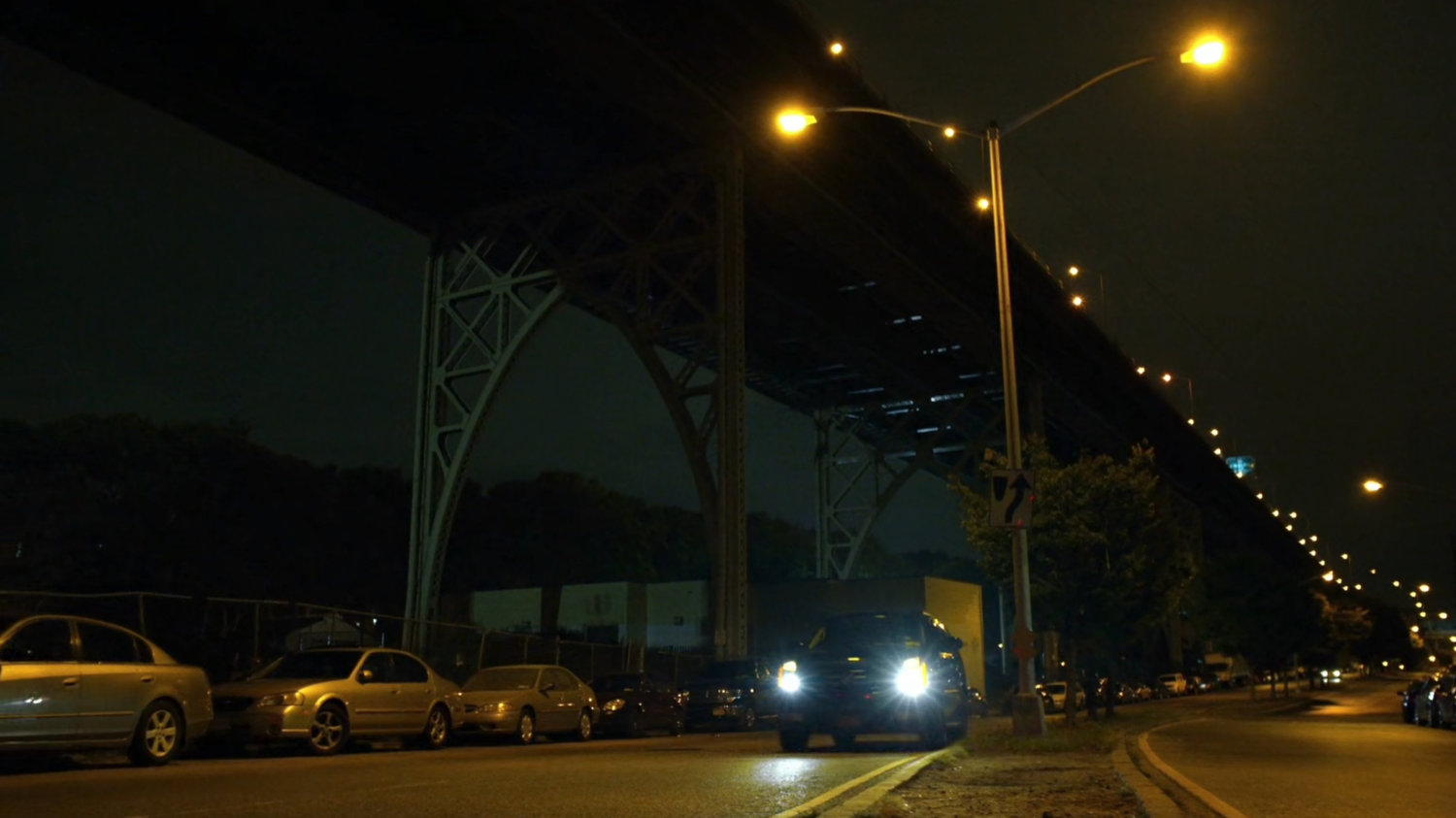 Black SUV on street under a bridge.