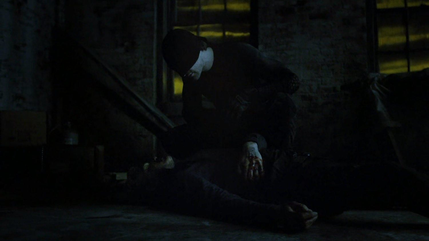 Daredevil kneeling over Vladimir inside abandoned warehouse.