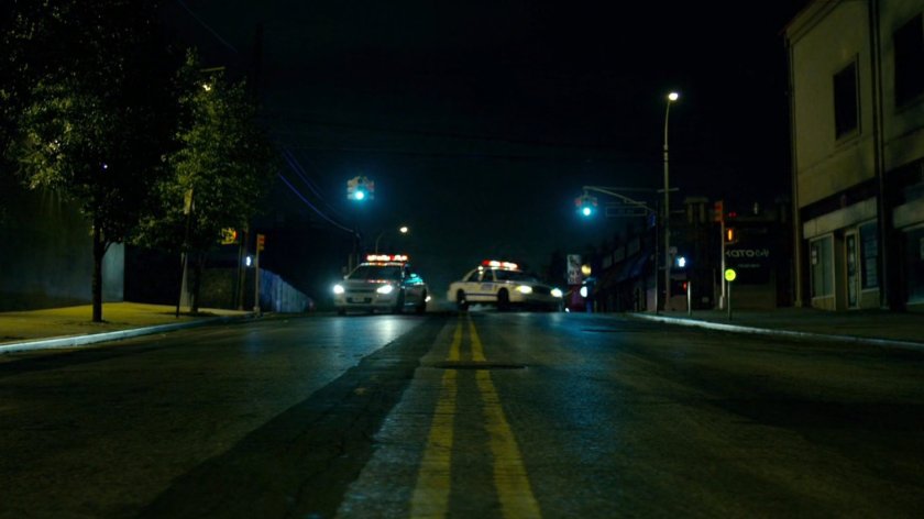 Police cars responding to hostage situation, racing around corner.