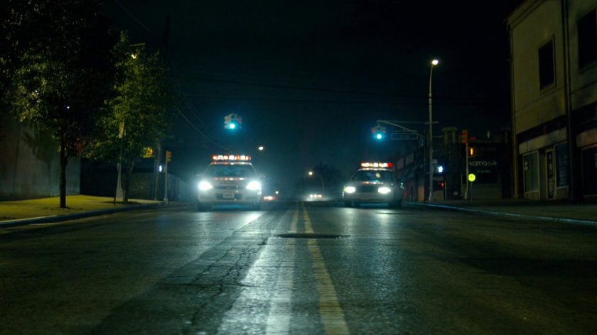 Police cars responding to hostage situation, racing around corner.