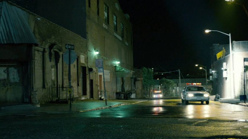 Police car on street outside of abandoned warehouse.