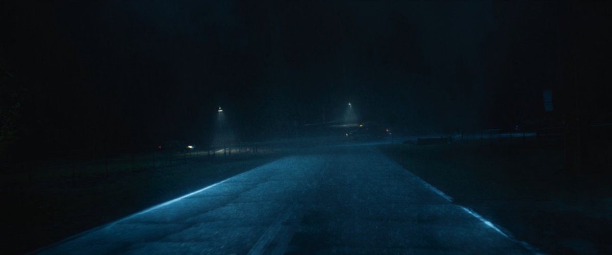 A rainy road and intersection at night.