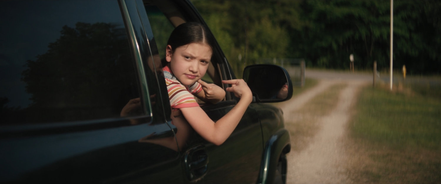 Young Maya in a car outside the Lopez house.